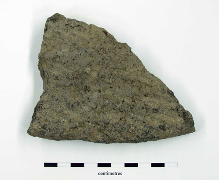 Small lump of lavastone quern, handle hole partially intact. 25mm thick