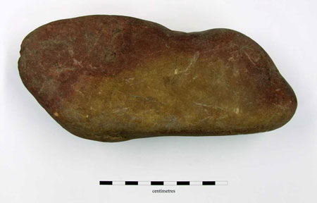 Large ?slickstone or whetstone. Area of metallic residue visible as well as area of fire-reddening. 197 x 86 x 63mm